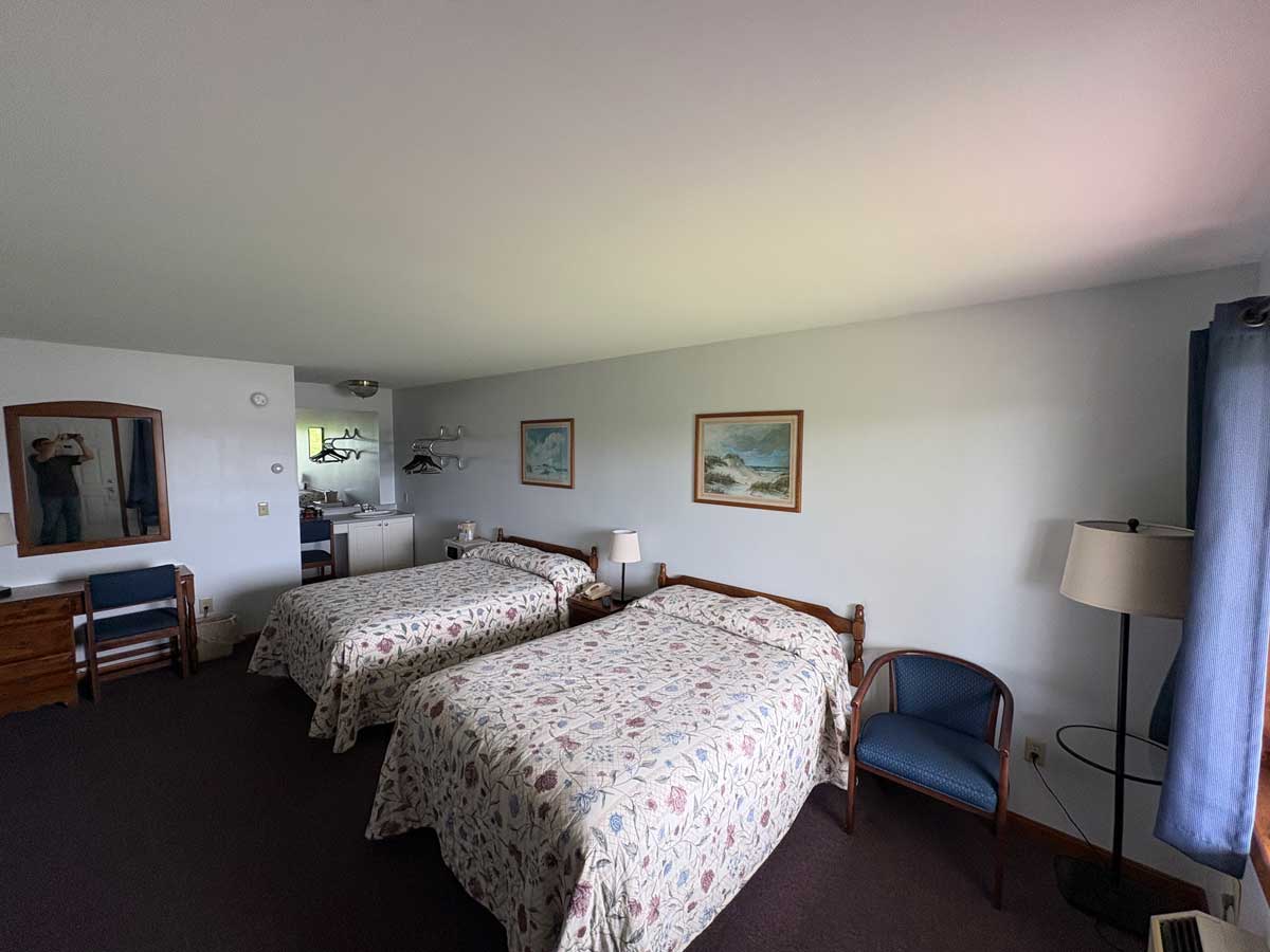 Riverview guest room with two double beds, seating area, mini kitchenette, and bright natural lighting.
