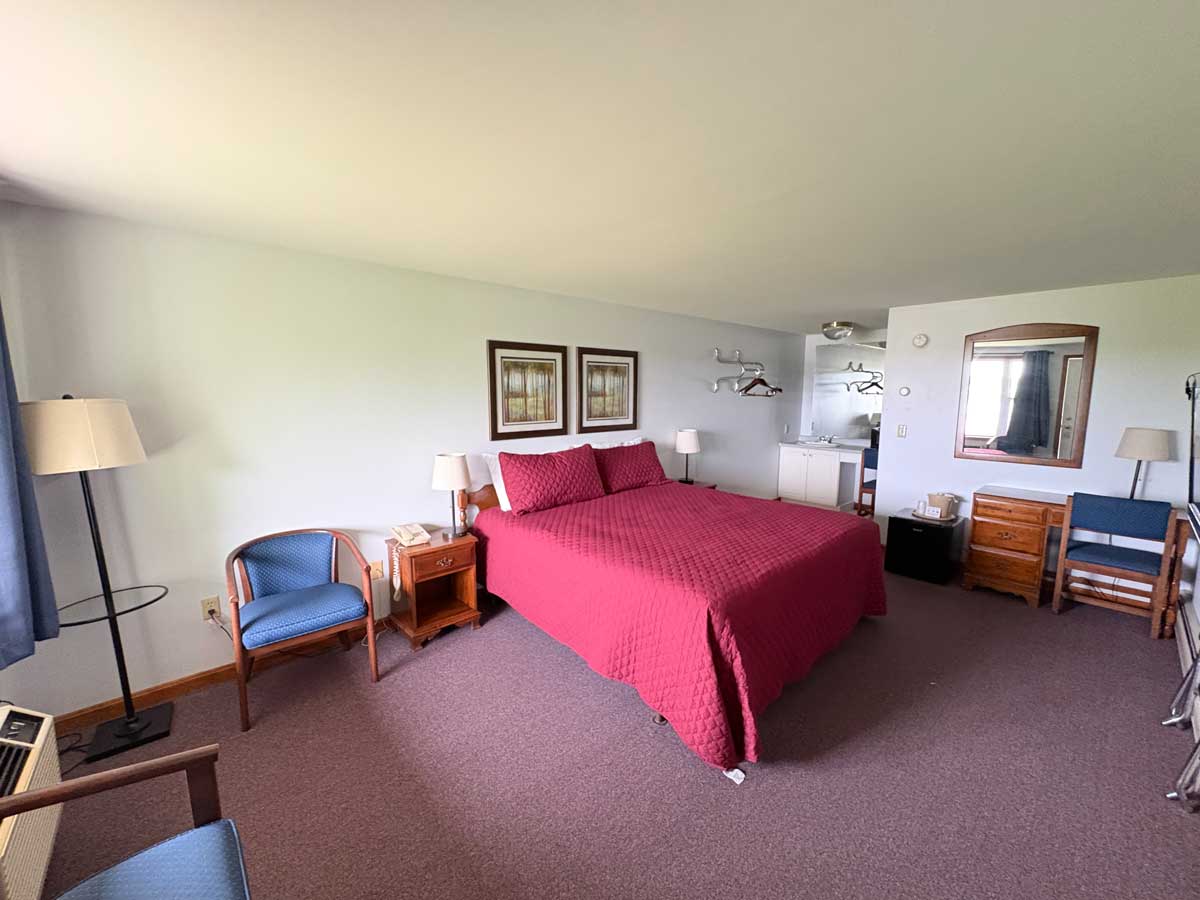 Riverview room featuring queen bed, kitchenette area, comfortable seating, and spacious accommodations.